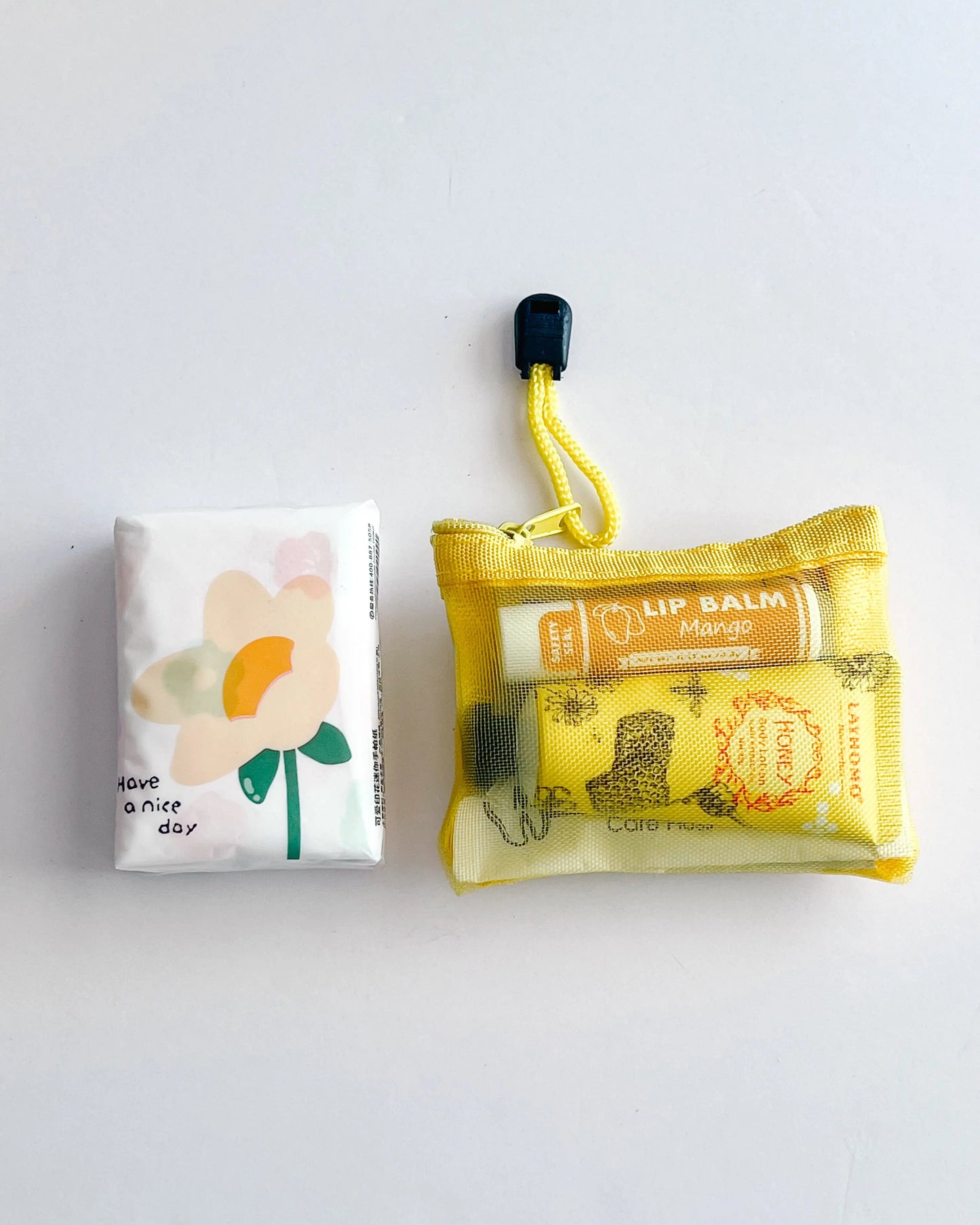 Compact Essential Pocket Kit flat lay with tissue pack and yellow mesh pouch