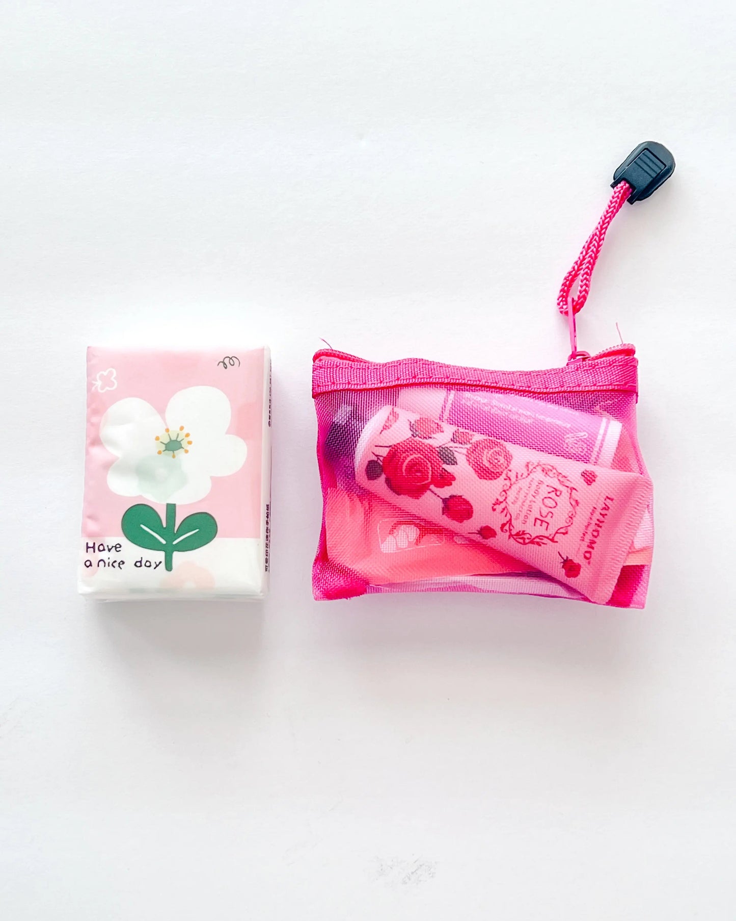 Compact Essential Pocket Kit flat lay with tissue pack and pink mesh pouch