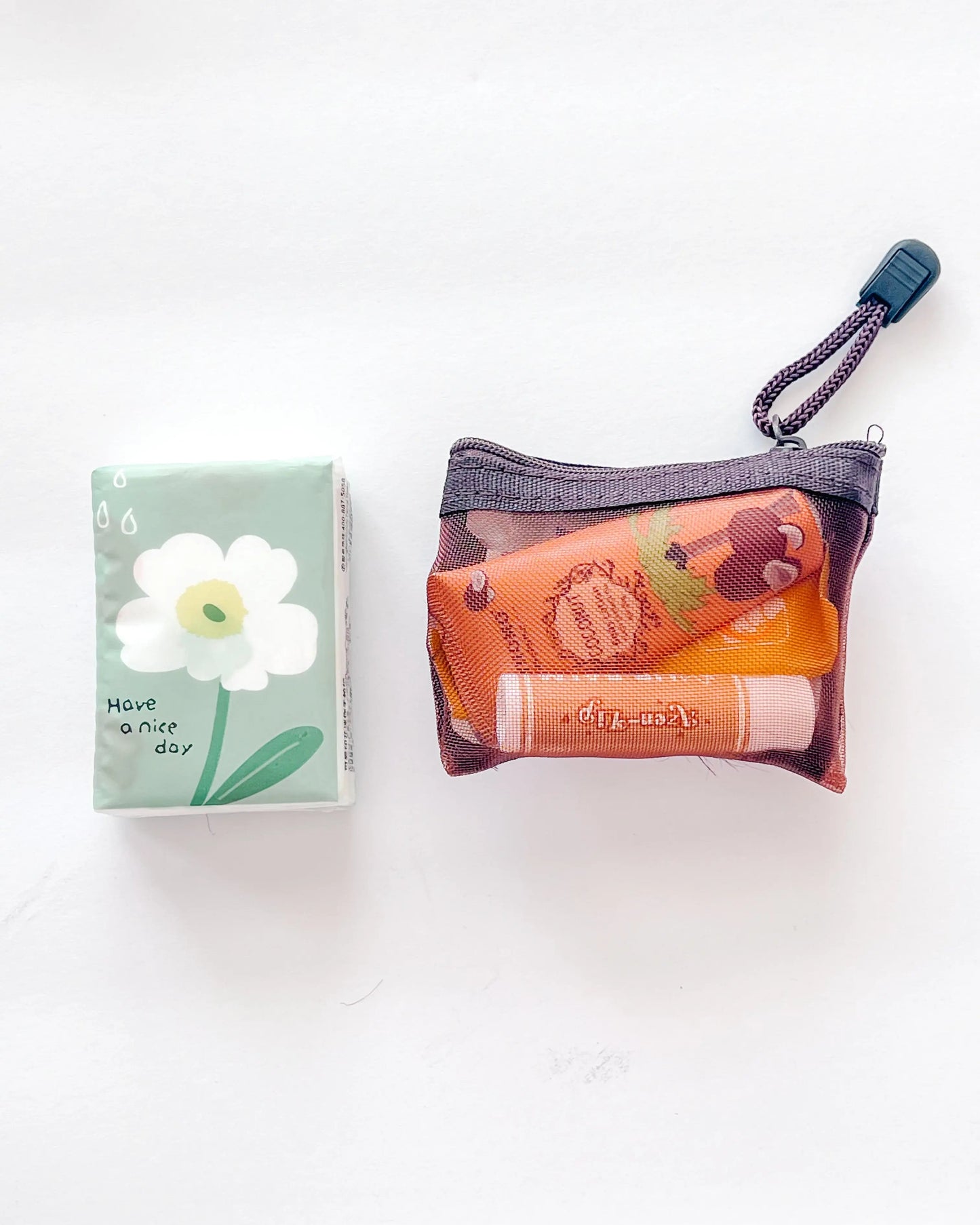 Compact Essential Pocket Kit flat lay with tissue pack and brown mesh pouch