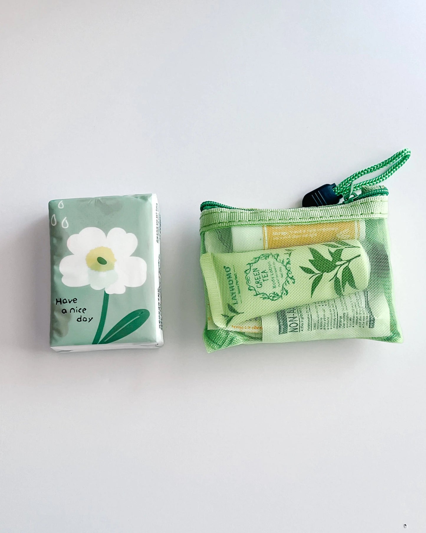 Compact Essential Pocket Kit flat lay with tissue pack and green mesh pouch