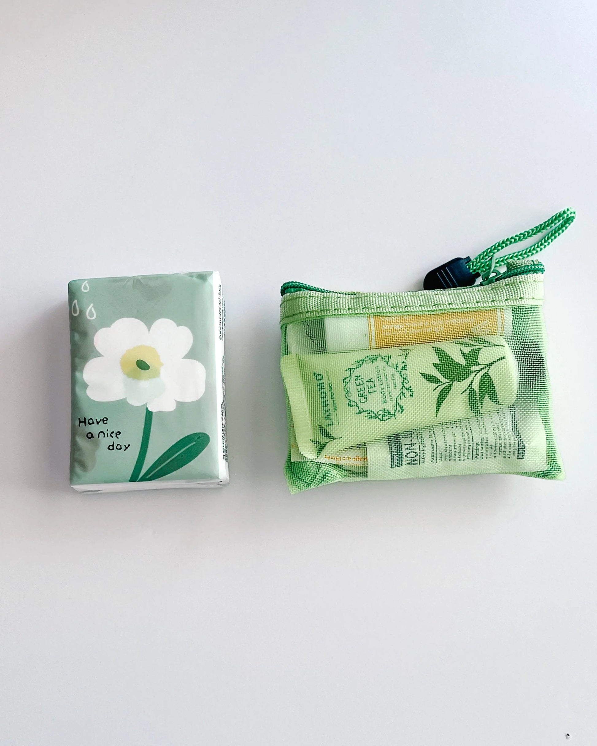 Compact Essential Pocket Kit flat lay with tissue pack and green mesh pouch
