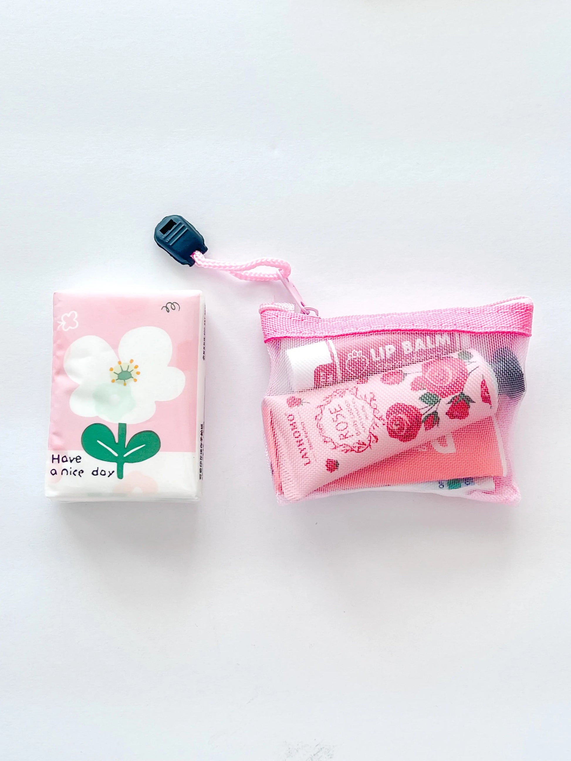 Compact Essential Pocket Kit flat lay with tissue pack and pink mesh pouch